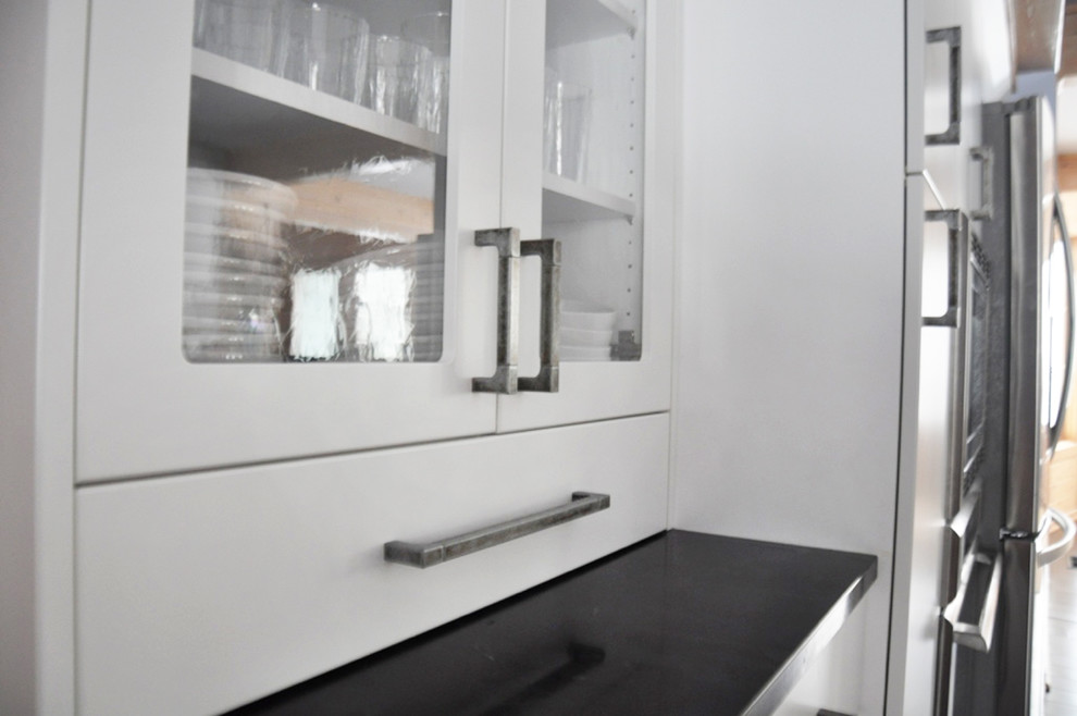 Inspiration for a mid-sized transitional l-shaped dark wood floor eat-in kitchen remodel in Grand Rapids with an undermount sink, flat-panel cabinets, white cabinets, soapstone countertops, white backsplash, subway tile backsplash, stainless steel appliances and an island