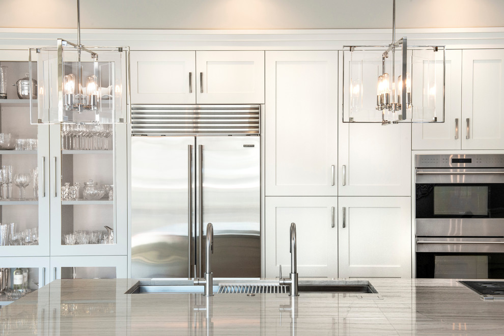 Inspiration for a large transitional medium tone wood floor and brown floor open concept kitchen remodel with an undermount sink, recessed-panel cabinets, white cabinets, quartzite countertops, brown backsplash, ceramic backsplash, stainless steel appliances, an island and white countertops
