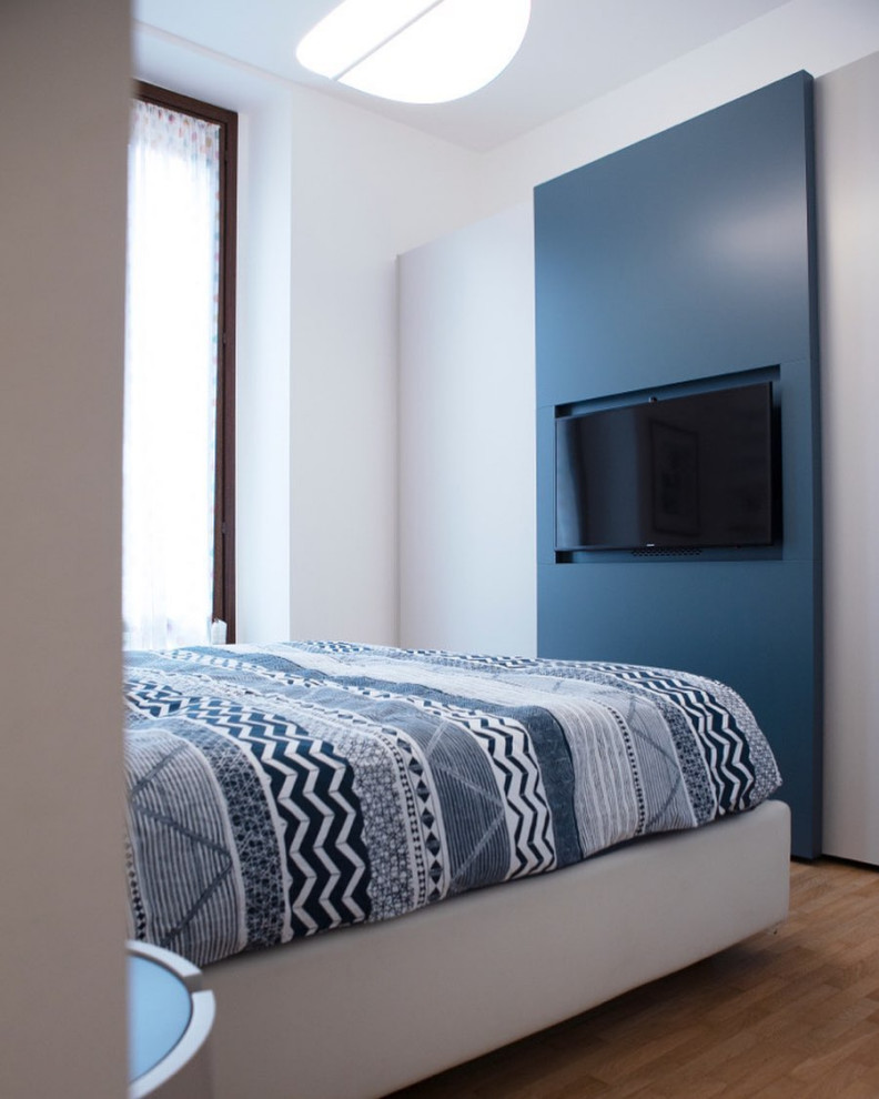 Geräumiges Modernes Hauptschlafzimmer ohne Kamin mit weißer Wandfarbe, hellem Holzboden, verputzter Kaminumrandung, beigem Boden und Tapetenwänden in Mailand