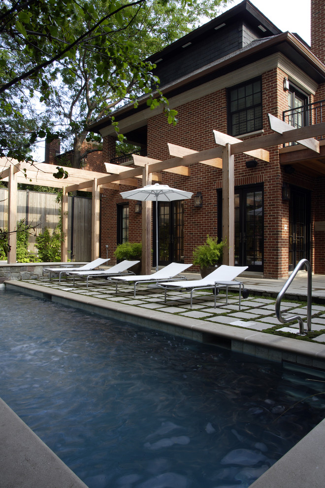 This is an example of a small modern courtyard rectangular lap pool in Chicago with natural stone pavers and a hot tub.
