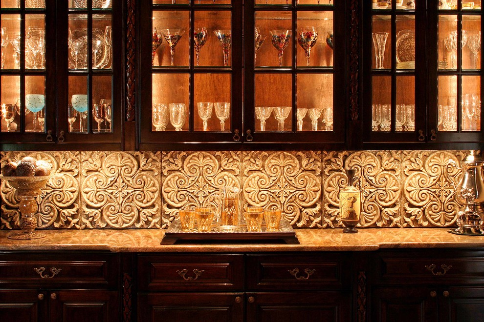 Mid-sized mediterranean single-wall home bar in Austin with raised-panel cabinets, dark wood cabinets, limestone benchtops, beige splashback and stone tile splashback.