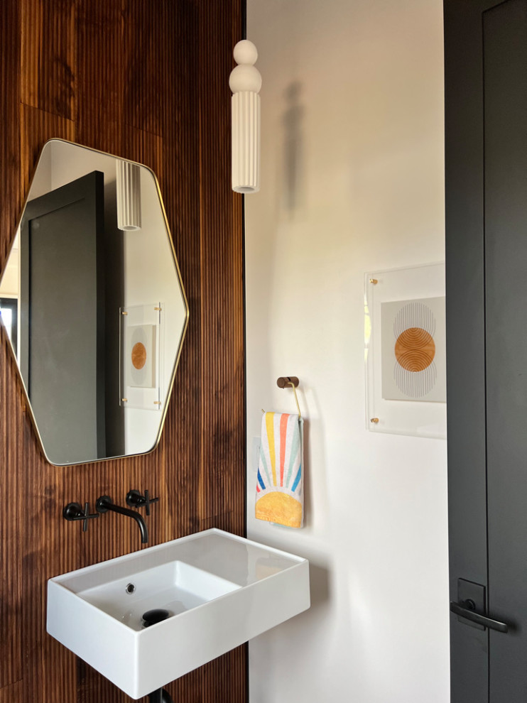 Imagen de aseo contemporáneo con sanitario de pared, paredes marrones, suelo de madera clara, lavabo suspendido y madera