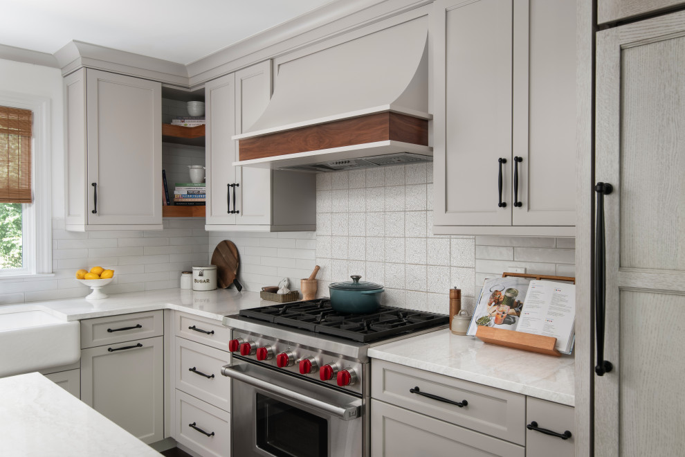 Inspiration for a mid-sized transitional l-shaped medium tone wood floor and brown floor eat-in kitchen remodel in New York with a farmhouse sink, shaker cabinets, beige cabinets, quartz countertops, white backsplash, porcelain backsplash, paneled appliances, an island and white countertops