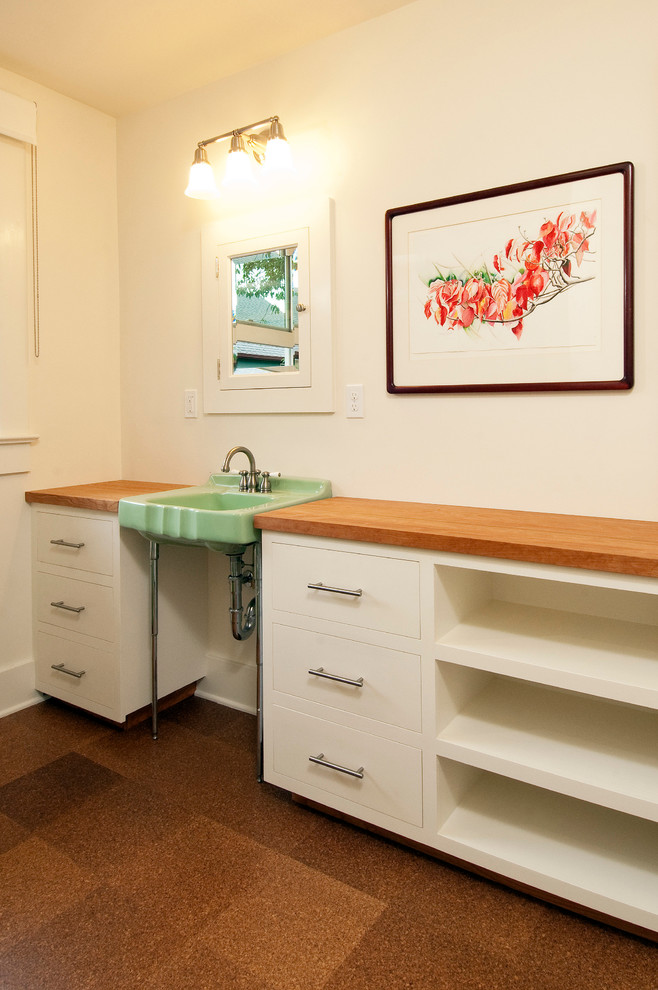 Photo of a traditional laundry room in Portland with a single-bowl sink, flat-panel cabinets, white cabinets, wood benchtops, white walls and cork floors.