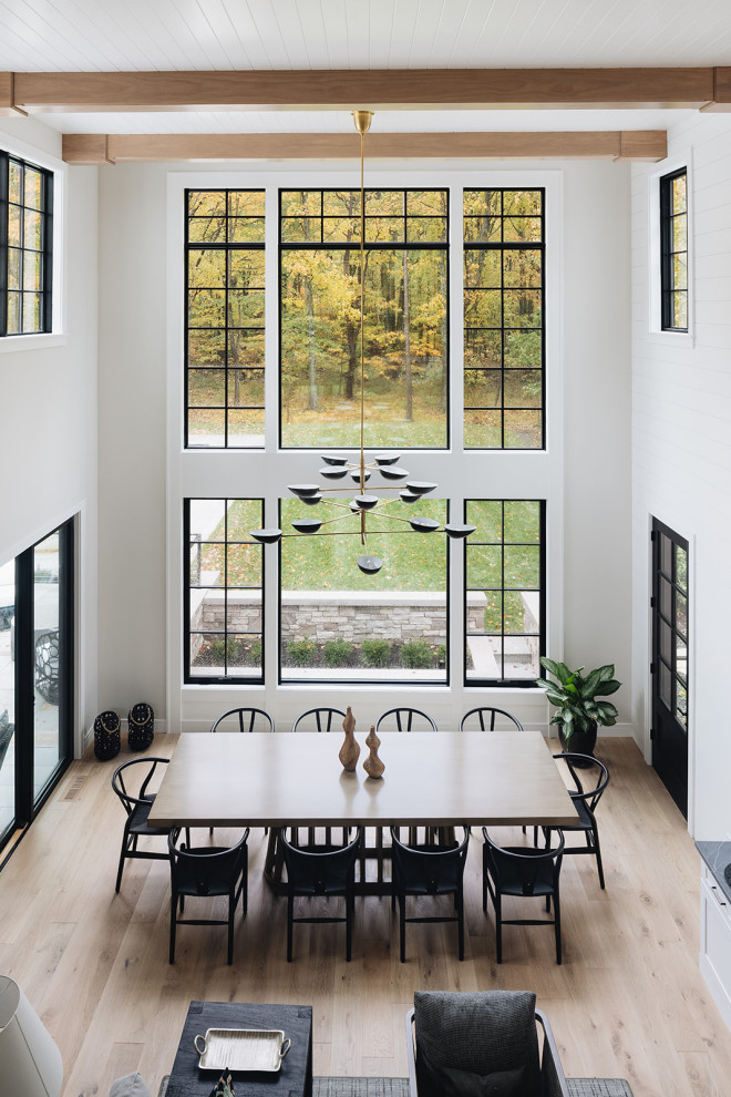 Ispirazione per una grande sala da pranzo aperta verso il soggiorno minimalista con pareti bianche, parquet chiaro, pavimento beige, pareti in perlinato e travi a vista