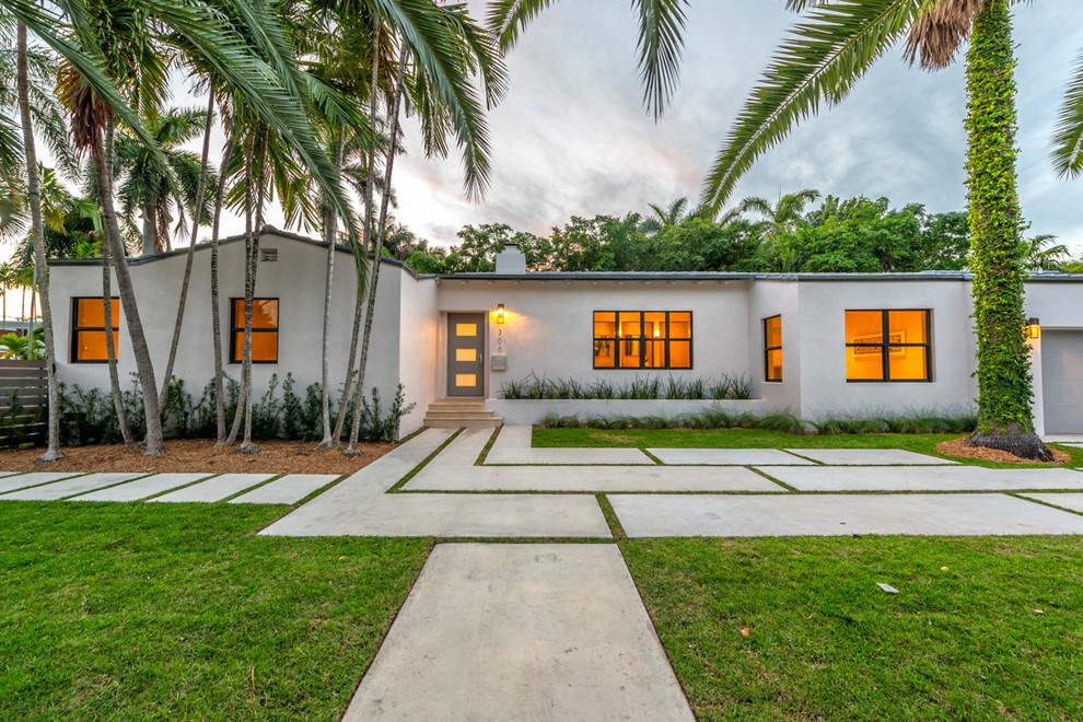 This is an example of a large tropical one-storey concrete white house exterior in Miami with a flat roof.