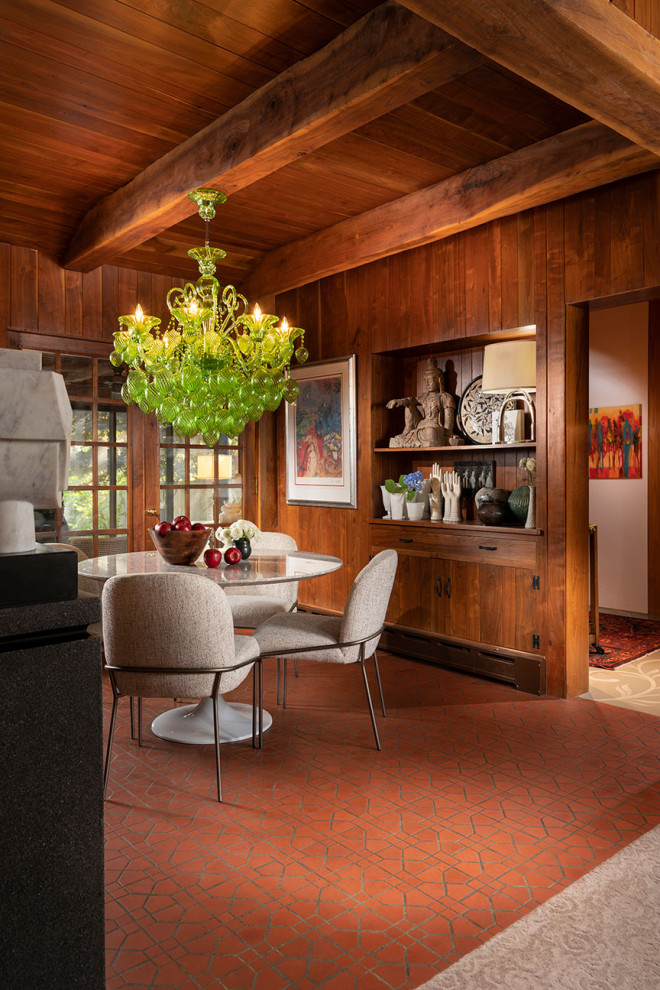 На фото: столовая в стиле рустика с коричневыми стенами, красным полом, балками на потолке, деревянным потолком и деревянными стенами