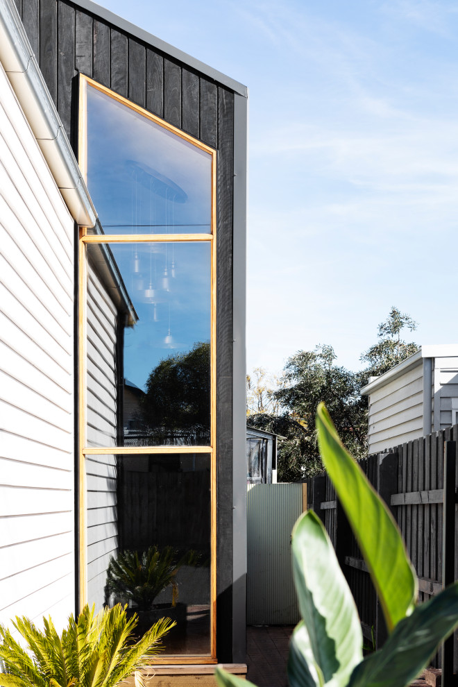 Photo of a scandinavian two-storey house exterior in Melbourne with wood siding and a metal roof.