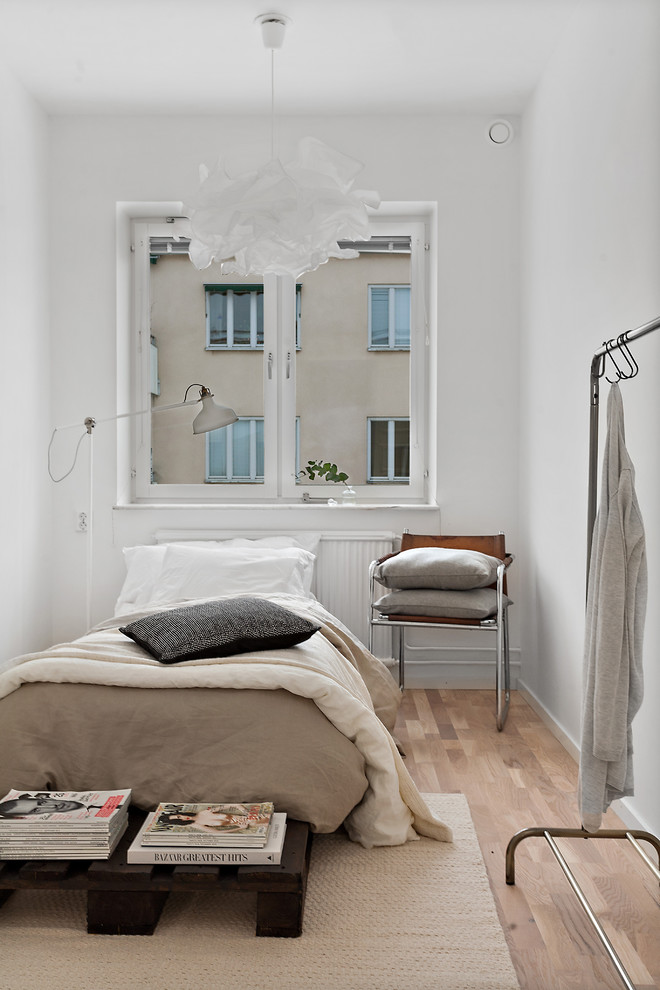 Design ideas for a mid-sized contemporary guest bedroom in Stockholm with white walls, medium hardwood floors and no fireplace.