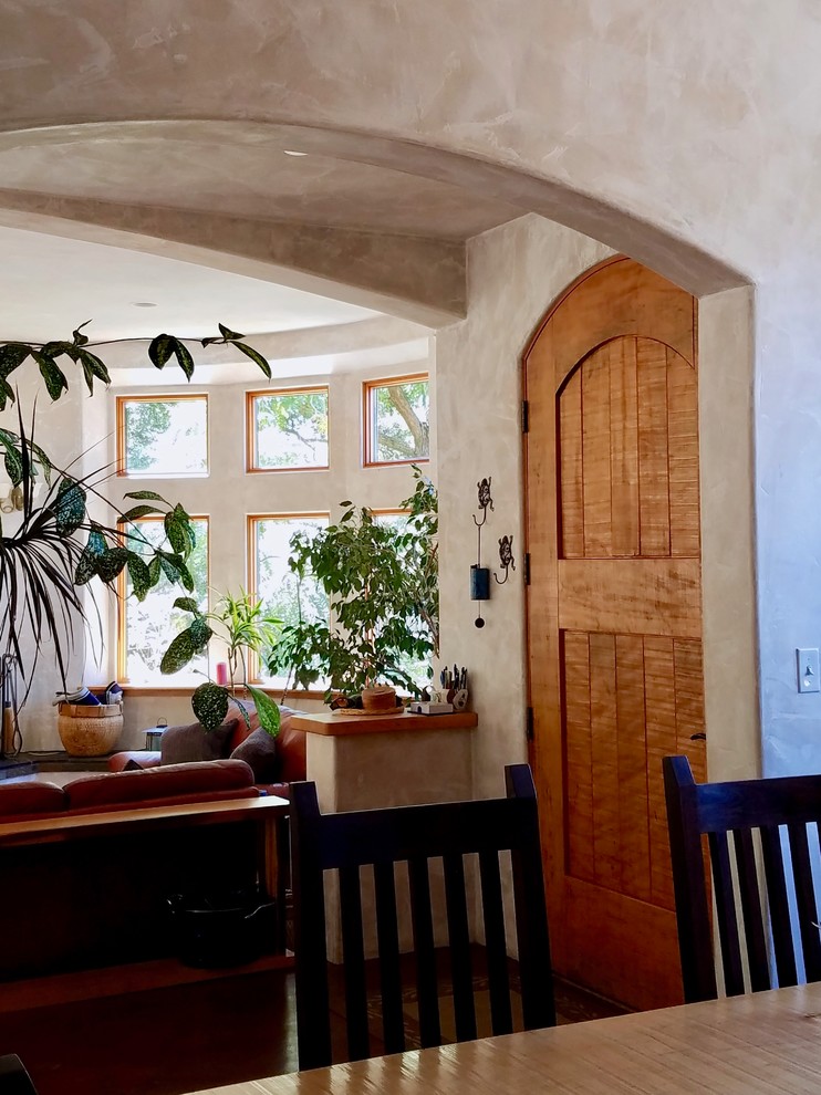 Photo of a small mediterranean front door in Other with beige walls, concrete floors, a single front door, a medium wood front door and brown floor.