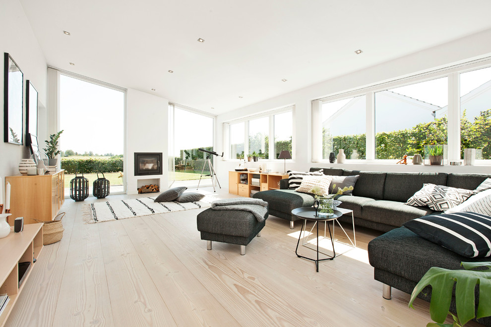 Large scandinavian formal open concept living room in Copenhagen with white walls, light hardwood floors, a standard fireplace, a brick fireplace surround and no tv.