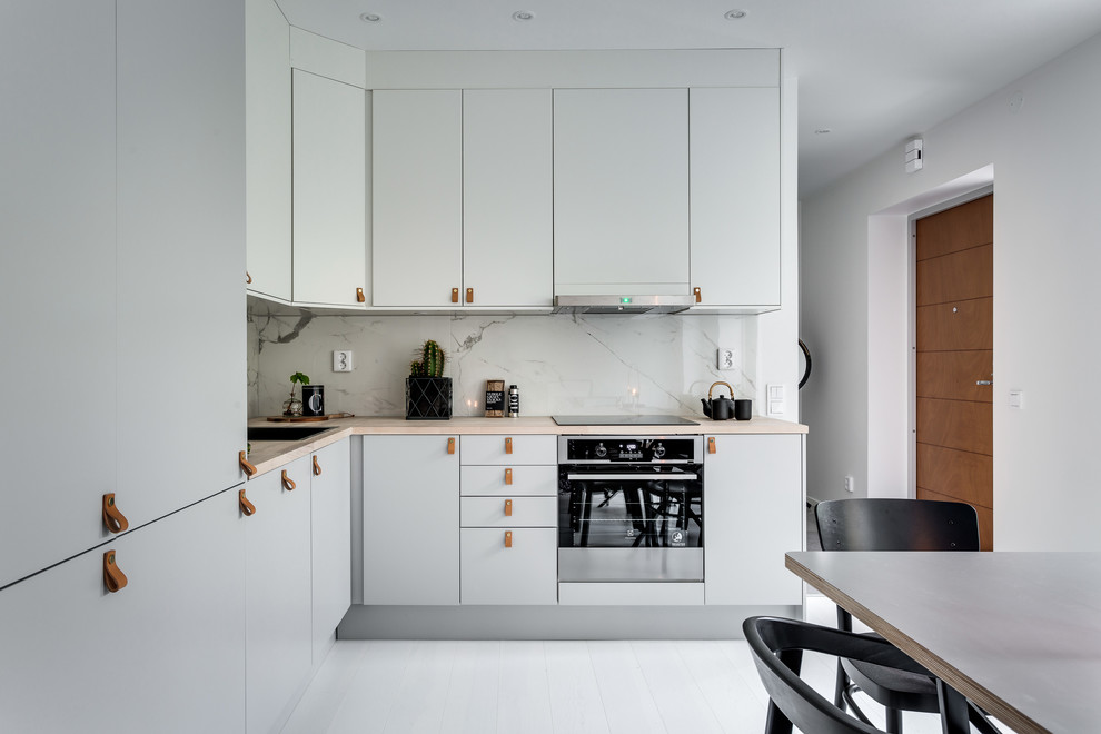 Large scandinavian l-shaped open plan kitchen in Stockholm with flat-panel cabinets, grey cabinets, wood benchtops, painted wood floors and no island.