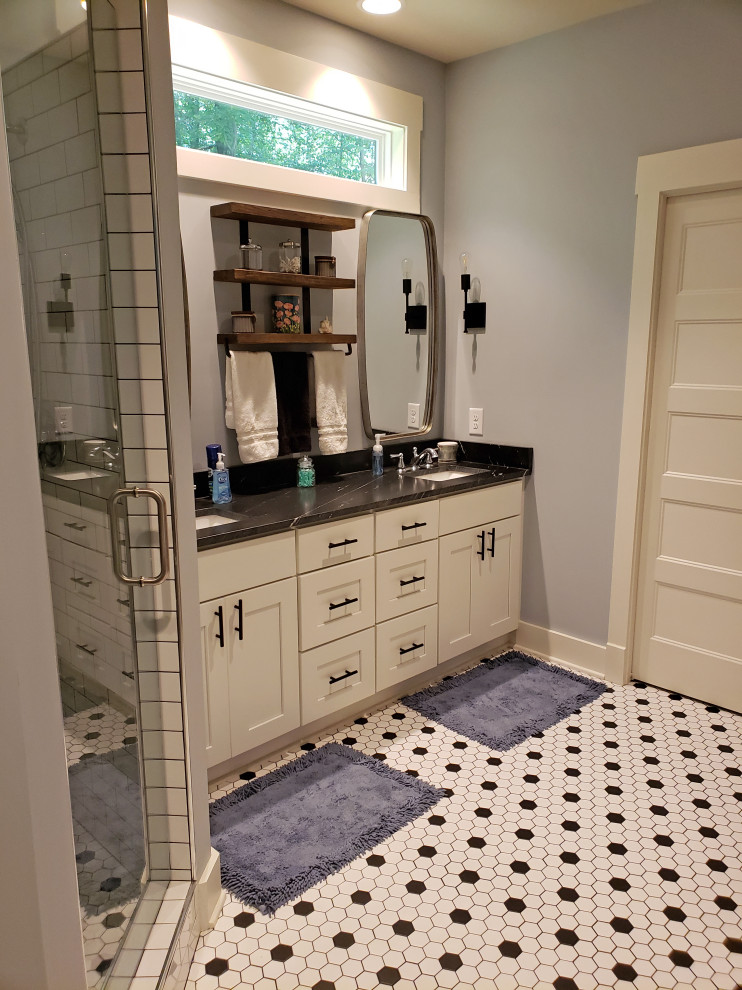 This is an example of a medium sized rural ensuite bathroom in Nashville with flat-panel cabinets, white cabinets, a corner shower, a one-piece toilet, white tiles, ceramic tiles, blue walls, porcelain flooring, a submerged sink, granite worktops, multi-coloured floors, a hinged door, black worktops, a shower bench, double sinks and a built in vanity unit.