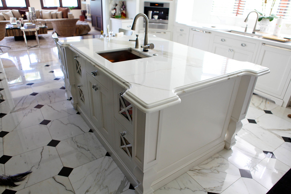 Photo of a large traditional u-shaped eat-in kitchen in Miami with a drop-in sink, recessed-panel cabinets, white cabinets, marble benchtops, white splashback, stone slab splashback, stainless steel appliances, marble floors and with island.
