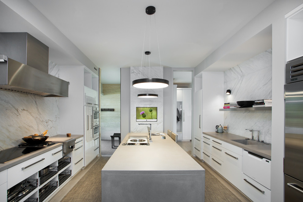 This is an example of a mid-sized contemporary u-shaped kitchen in Other with an integrated sink, flat-panel cabinets, white cabinets, concrete benchtops, white splashback, marble splashback, stainless steel appliances, with island and brown floor.