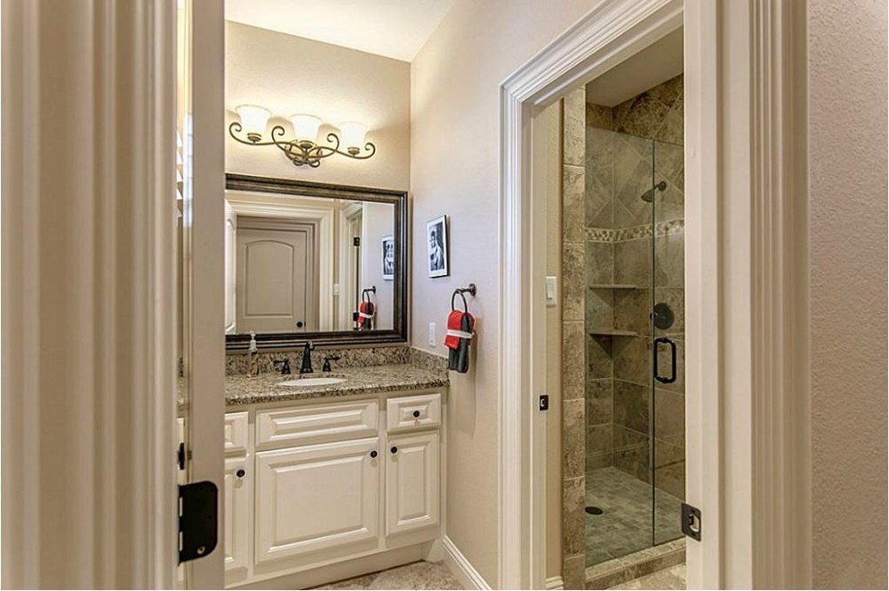 Inspiration for a large mediterranean kids bathroom in Houston with raised-panel cabinets, white cabinets, granite benchtops, an alcove shower, beige tile, ceramic tile, beige walls and travertine floors.