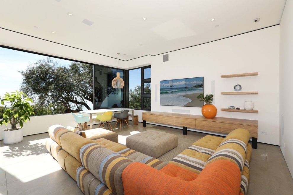 Photo of a mid-sized contemporary enclosed family room in Orange County with white walls, grey floor, no fireplace and a wall-mounted tv.
