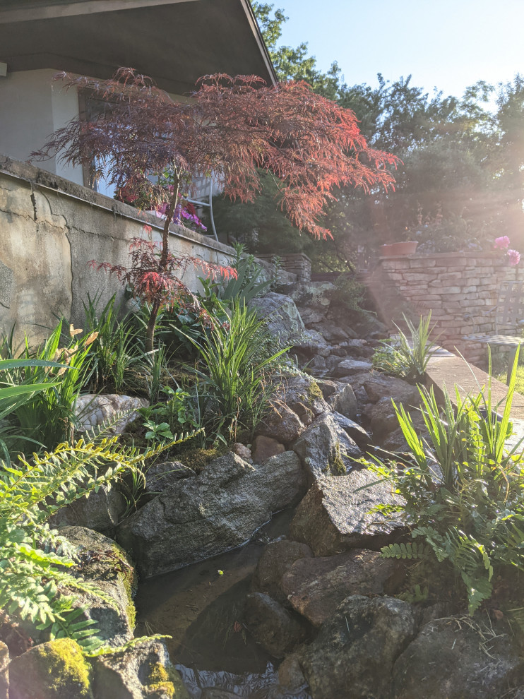This is an example of a mid-sized asian garden in Other with with waterfall.