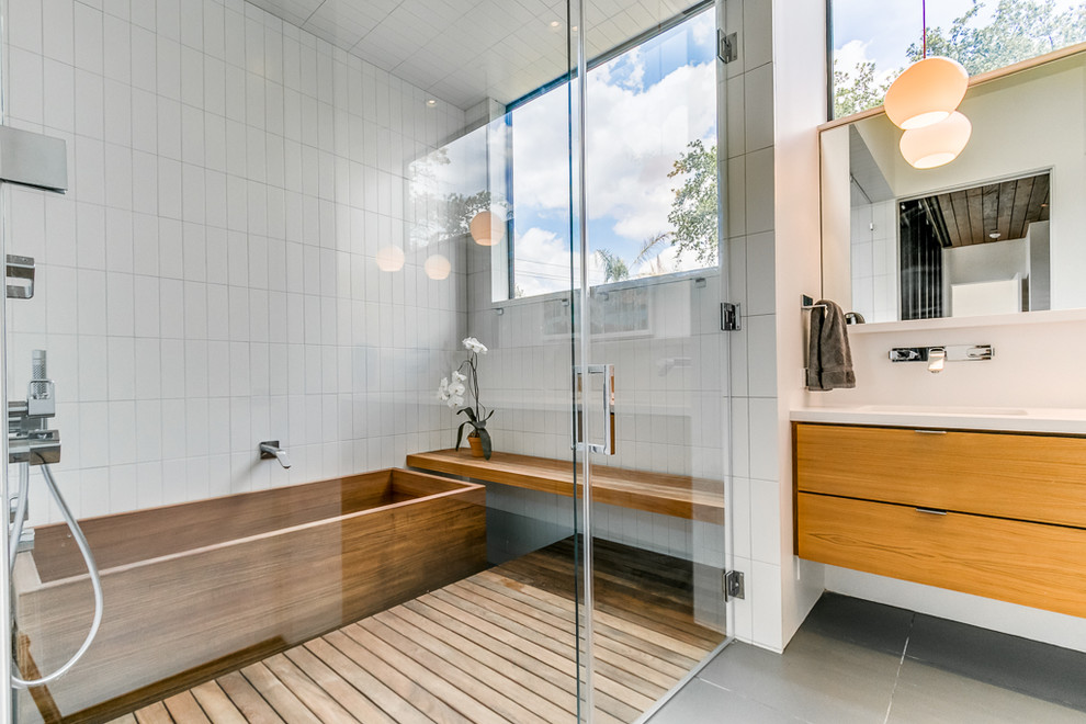 Mid-sized modern master bathroom in Houston with flat-panel cabinets, medium wood cabinets, a japanese tub, a shower/bathtub combo, white tile, ceramic tile, white walls, ceramic floors, an undermount sink, engineered quartz benchtops, grey floor and a hinged shower door.