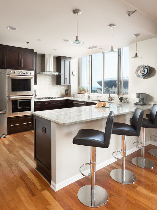 Open concept kitchen - mid-sized transitional u-shaped medium tone wood floor open concept kitchen idea in Chicago with an undermount sink, shaker cabinets, dark wood cabinets, marble countertops, white backsplash, subway tile backsplash, stainless steel appliances and a peninsula