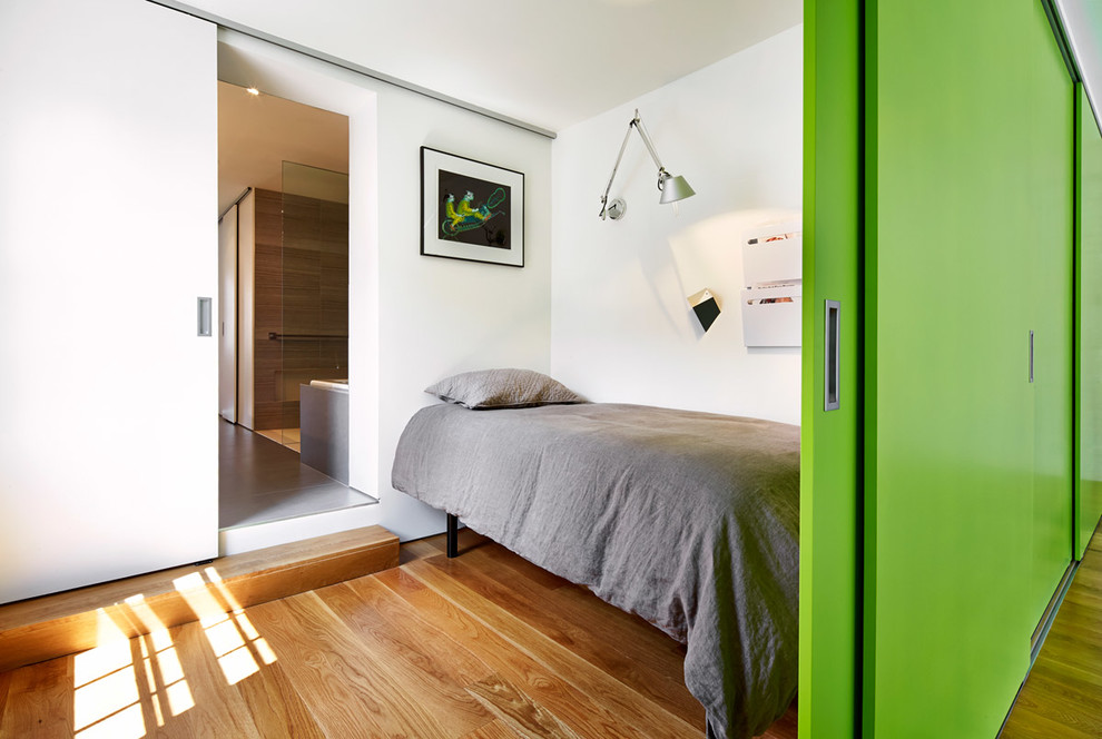 Photo of a small contemporary bedroom in DC Metro with white walls and medium hardwood floors.