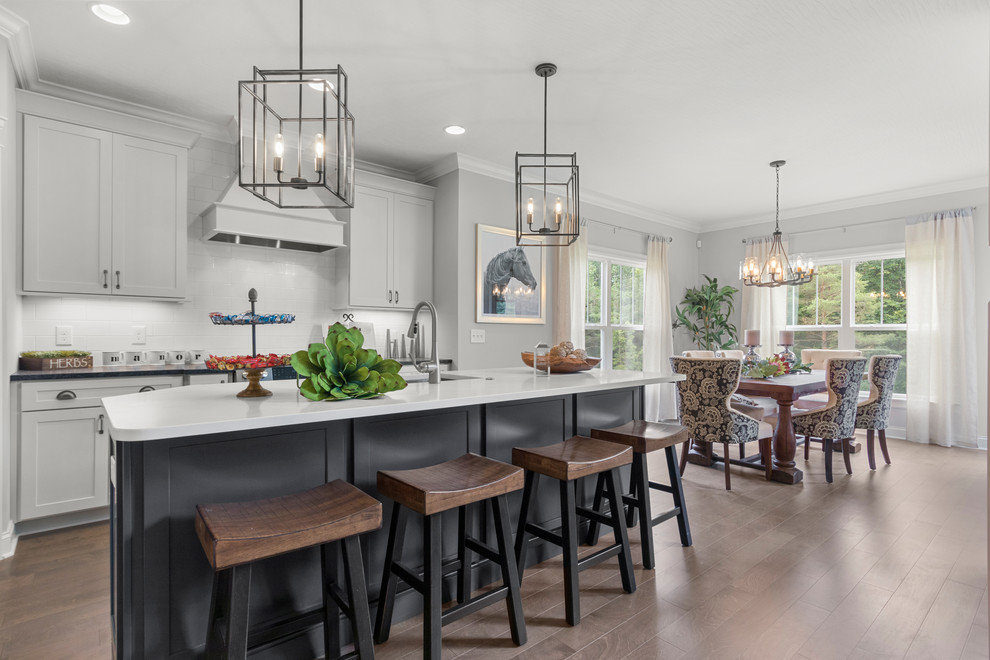 Transitional dark wood floor and brown floor eat-in kitchen photo in Columbus with an undermount sink, shaker cabinets, gray cabinets, white backsplash, an island and black countertops