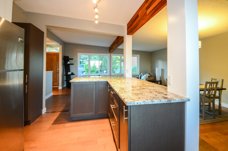 Inspiration for a small transitional l-shaped medium tone wood floor open concept kitchen remodel in Calgary with an undermount sink, shaker cabinets, dark wood cabinets, marble countertops, multicolored backsplash, matchstick tile backsplash, stainless steel appliances and an island