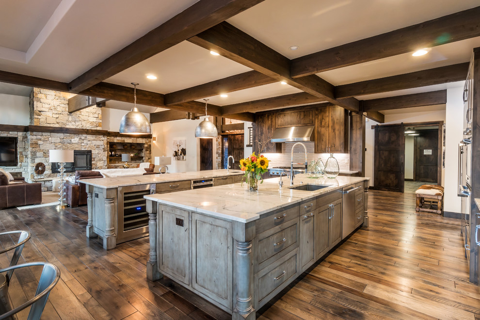 Inspiration for an expansive country u-shaped open plan kitchen in Other with an undermount sink, recessed-panel cabinets, distressed cabinets, quartzite benchtops, grey splashback, porcelain splashback, stainless steel appliances, medium hardwood floors and multiple islands.
