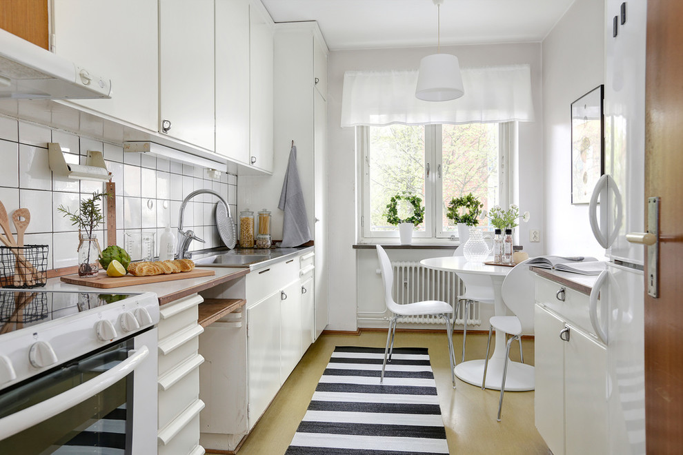 Inspiration for a scandinavian single-wall eat-in kitchen in Malmo with an integrated sink, flat-panel cabinets, white cabinets, white splashback, white appliances and yellow floor.