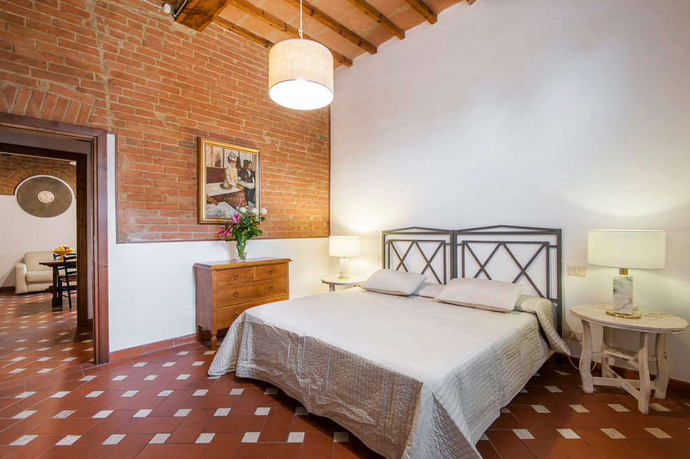 Photo of a country bedroom in Florence with red walls, terra-cotta floors and red floor.