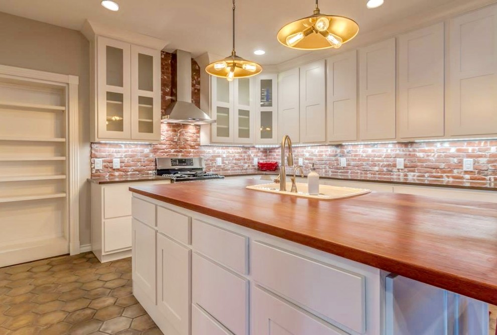 Enclosed kitchen - large transitional u-shaped beige floor and terra-cotta tile enclosed kitchen idea in Austin with a drop-in sink, shaker cabinets, white cabinets, red backsplash, brick backsplash, stainless steel appliances, an island, gray countertops and granite countertops