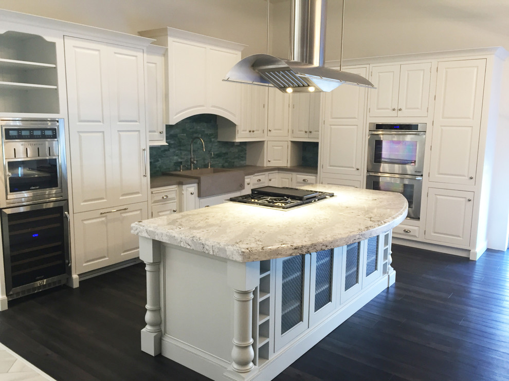 This is an example of a large transitional l-shaped eat-in kitchen in Phoenix with a farmhouse sink, recessed-panel cabinets, white cabinets, green splashback, glass tile splashback, stainless steel appliances, vinyl floors, with island and concrete benchtops.
