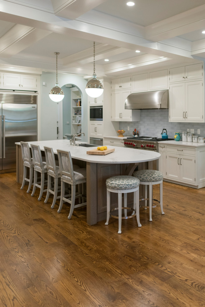 Large transitional l-shaped kitchen in DC Metro with an undermount sink, shaker cabinets, white cabinets, grey splashback, stainless steel appliances, medium hardwood floors, with island, brown floor, white benchtop and coffered.