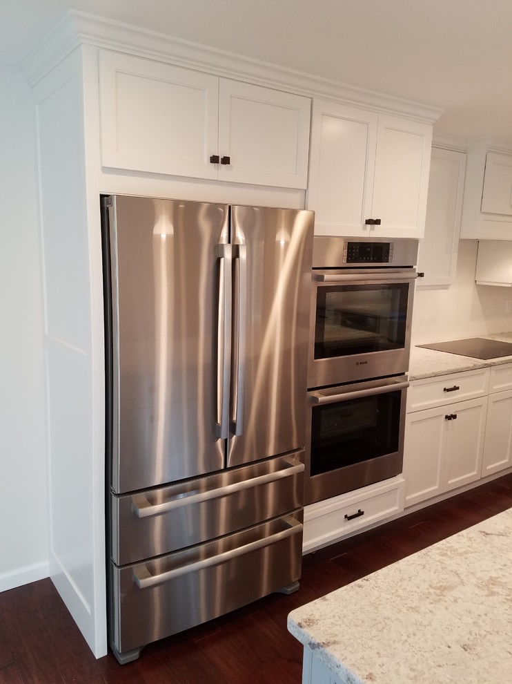Eat-in kitchen - mid-sized transitional l-shaped dark wood floor and brown floor eat-in kitchen idea with a farmhouse sink, shaker cabinets, white cabinets, granite countertops, white backsplash, subway tile backsplash, stainless steel appliances and an island