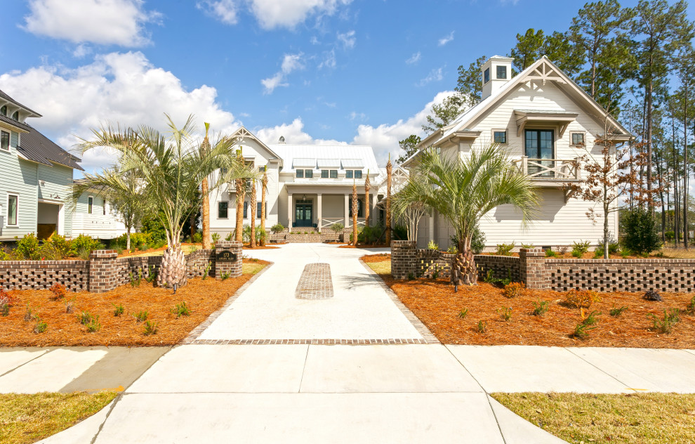 Large beach style two-storey beige house exterior in Charleston with concrete fiberboard siding, a gable roof and a metal roof.