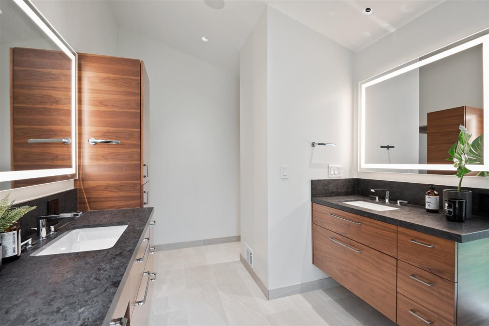 Design ideas for a large midcentury ensuite bathroom in San Francisco with flat-panel cabinets, medium wood cabinets, a built-in shower, a one-piece toilet, grey tiles, ceramic tiles, wood-effect flooring, solid surface worktops, an open shower, black worktops, a floating vanity unit and a vaulted ceiling.