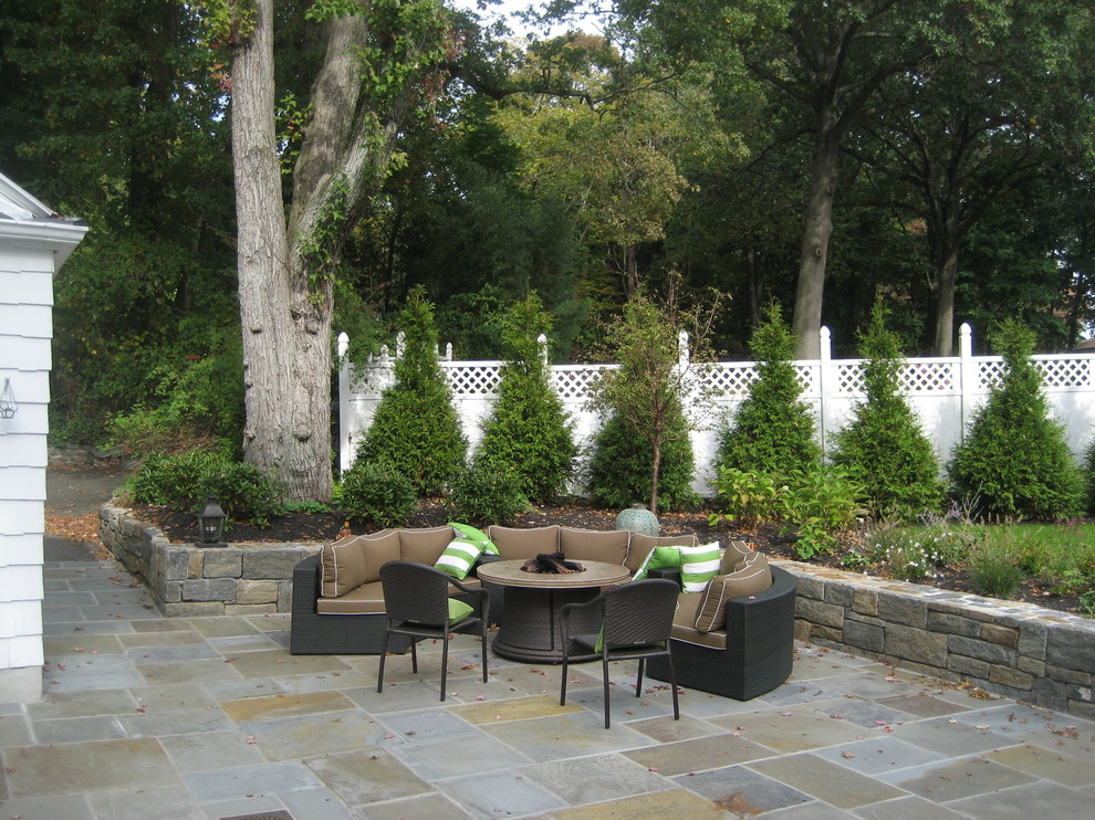 Large traditional backyard garden in New York with a fire feature and natural stone pavers.