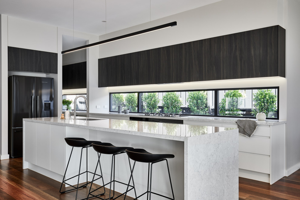 メルボルンにあるラグジュアリーな広いコンテンポラリースタイルのおしゃれなアイランドキッチン (アンダーカウンターシンク、ガラスまたは窓のキッチンパネル、シルバーの調理設備、無垢フローリング、茶色い床) の写真