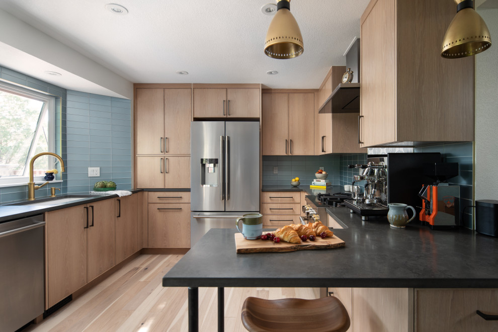 Inspiration for a contemporary u-shaped separate kitchen in Denver with an undermount sink, light wood cabinets, quartz benchtops, blue splashback, glass tile splashback, stainless steel appliances, light hardwood floors and black benchtop.