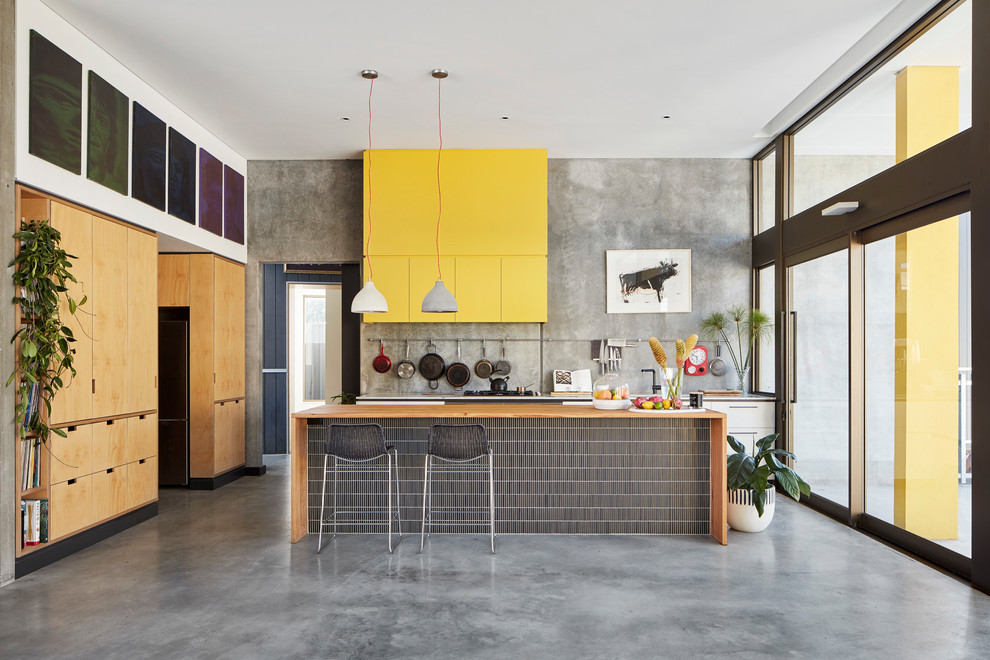 This is an example of a mid-sized industrial galley kitchen in Perth with flat-panel cabinets, concrete floors and with island.