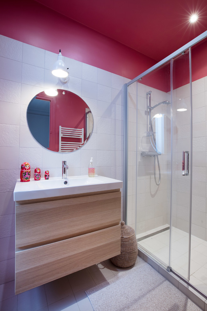 Photo of a small contemporary master bathroom in Paris with light wood cabinets, an alcove shower, white tile, pink walls, white floor, a sliding shower screen, flat-panel cabinets and a wall-mount sink.