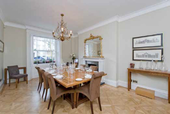 Photo of a medium sized enclosed dining room in London with grey walls, light hardwood flooring, a wood burning stove, a wooden fireplace surround and beige floors.