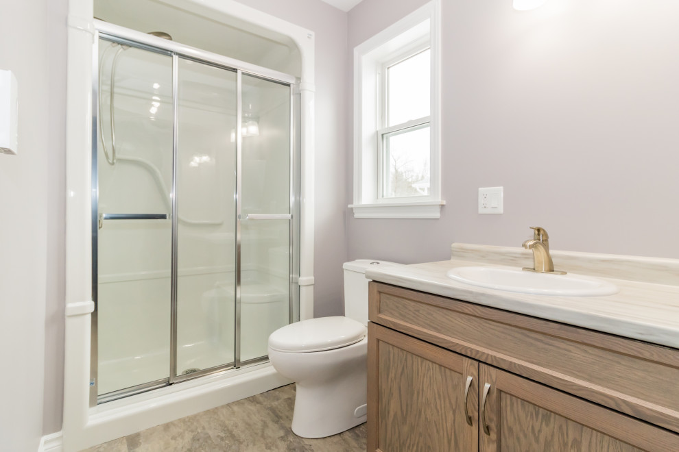 Small bathroom in Other with recessed-panel cabinets, brown cabinets, an alcove tub, a shower/bathtub combo, a one-piece toilet, purple walls, vinyl floors, a drop-in sink, laminate benchtops, blue floor, a sliding shower screen, beige benchtops, a single vanity and a built-in vanity.