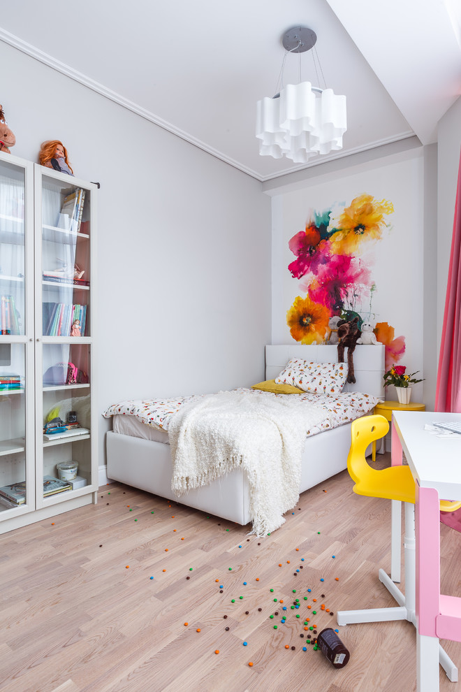 This is an example of a contemporary kids' bedroom for girls and kids 4-10 years old in Other with white walls, light hardwood floors and beige floor.