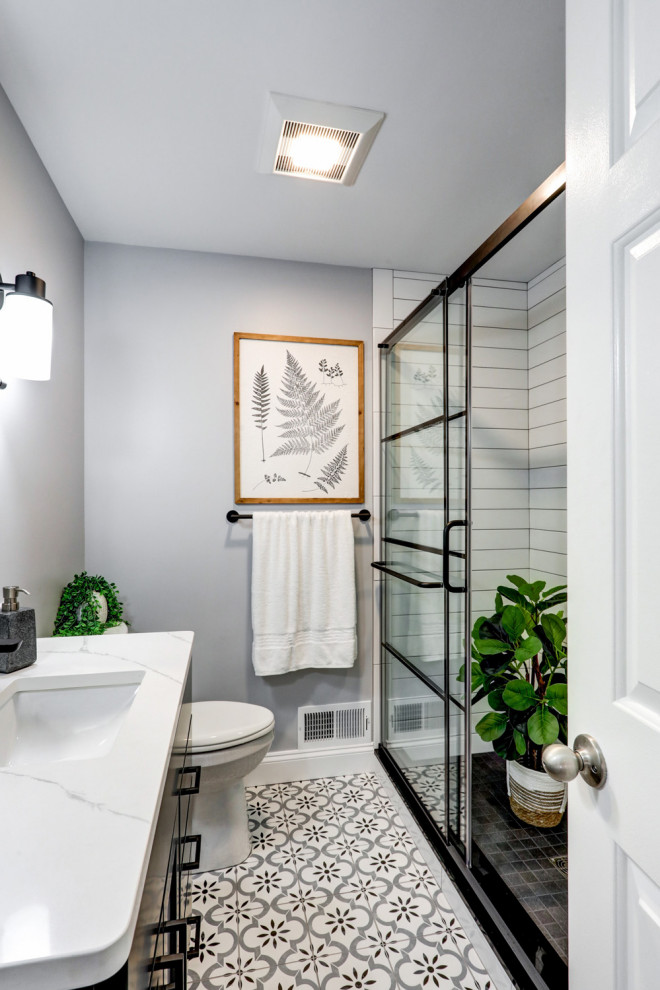 Источник вдохновения для домашнего уюта: маленькая ванная комната в стиле модернизм с фасадами с утопленной филенкой, черными фасадами, душем в нише, раздельным унитазом, белой плиткой, керамической плиткой, серыми стенами, полом из керамогранита, врезной раковиной, столешницей из искусственного кварца, разноцветным полом, душем с раздвижными дверями, белой столешницей, нишей, тумбой под одну раковину и встроенной тумбой для на участке и в саду