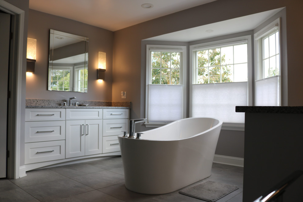 Klassisk inredning av ett stort grå grått en-suite badrum, med skåp i shakerstil, vita skåp, ett fristående badkar, grå kakel, porslinskakel, klinkergolv i porslin, ett undermonterad handfat, bänkskiva i kvarts, grått golv och dusch med gångjärnsdörr