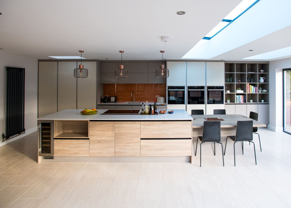 This is an example of an expansive contemporary galley kitchen in Hampshire with an undermount sink, flat-panel cabinets, grey cabinets, brown splashback, glass sheet splashback, panelled appliances, with island, beige floor and white benchtop.
