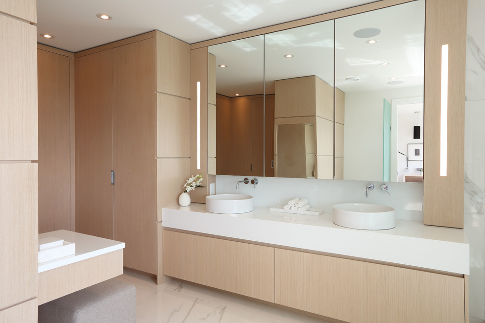 Photo of a large contemporary master bathroom in Vancouver with flat-panel cabinets, light wood cabinets, a freestanding tub, a corner shower, a one-piece toilet, white tile, glass sheet wall, white walls, ceramic floors, a vessel sink, engineered quartz benchtops, beige floor, a hinged shower door and white benchtops.
