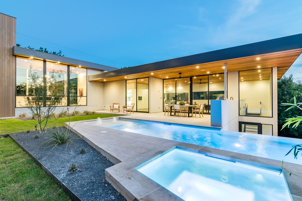 Photo of a contemporary rectangular infinity pool in Austin with a hot tub and concrete pavers.