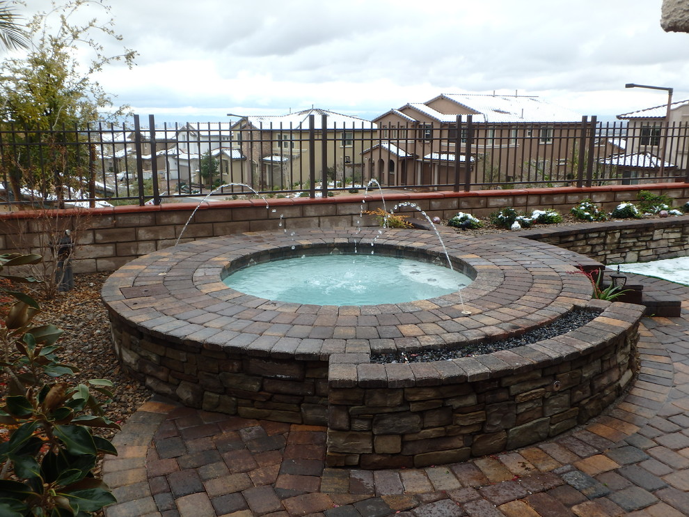 This is an example of a small mediterranean backyard round pool in Las Vegas with a hot tub and brick pavers.
